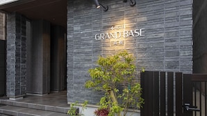 A hotel entrance with a stone facade and a sign reading "HOTEL GRAND BASE."