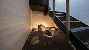 A modern staircase with glass railings, a stone floor, and a warm light source.