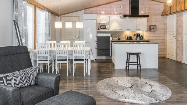 Een moderne keuken met witte kasten, een centraal eiland en een eetgedeelte met een tafel en stoelen.