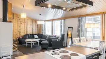 A modern kitchen with a central island, a dining area with a table and chairs, and a cozy seating area with a sofa and armchairs.