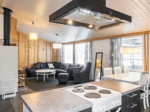 A modern kitchen with a central island, a dining area with a table and chairs, and a cozy seating area with a sofa and armchairs.