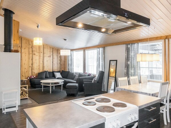 A modern kitchen with a central island, a dining area with a table and chairs, and a cozy seating area with a sofa and armchairs. - Aarre a by Interhome (Inari)