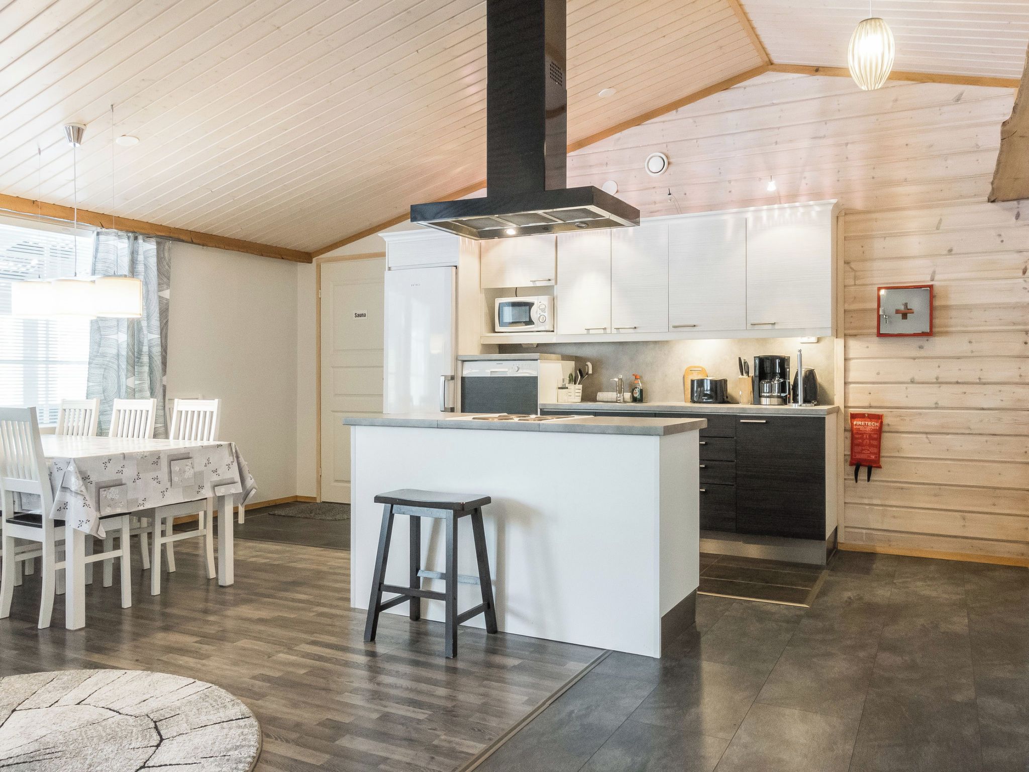 Une cuisine moderne dotée d’un îlot central, de planchers en bois et d’un coin repas avec une table et des chaises.
