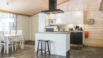 Une cuisine moderne dotée d’un îlot central, de planchers en bois et d’un coin repas avec une table et des chaises.