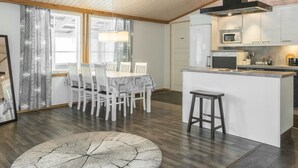 Een moderne keuken met witte kasten, een centraal eiland en een eetgedeelte met witte stoelen.