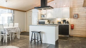 Een moderne keuken met witte kasten, een centraal eiland en een zwarte afzuigkap.