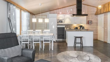 Une cuisine moderne dotée d’un îlot central, de meubles blancs et d’un four à micro-ondes encastré.