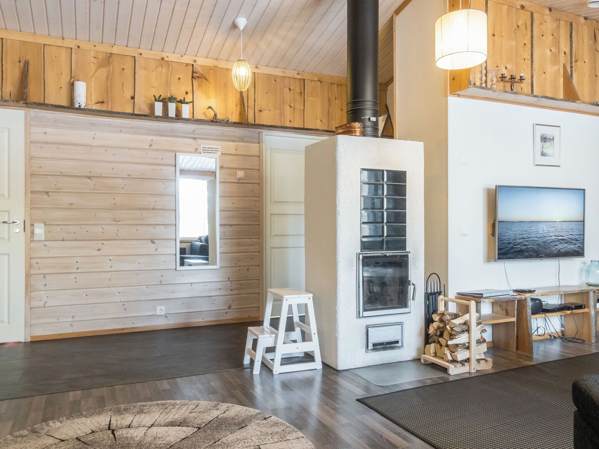 Un intérieur chaleureux avec des murs en bois, une cheminée, un téléviseur et une échelle.