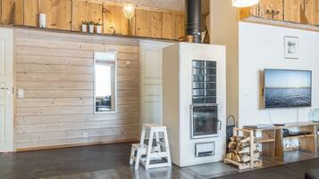 Un intérieur chaleureux avec des murs en bois, une cheminée, un téléviseur et une échelle.