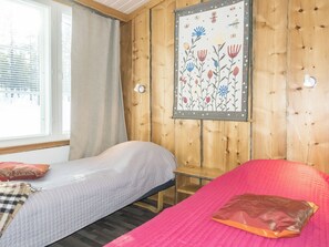 Een kamer met twee bedden, een raam met gordijnen en een kunstwerk aan de muur.