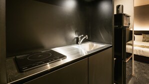 Uma cozinha moderna com fogão de indução embutido, cuba de aço inoxidável e geladeira compacta.
