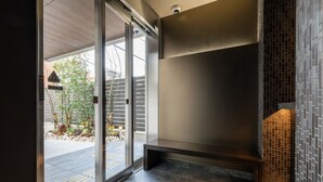Um interior moderno com um banco, uma porta de vidro que dá para o exterior e uma parede revestida com azulejos.