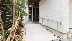 Um edifício moderno com fachada de tijolos brancos, um caminho pavimentado e um guarda-corpo de metal.