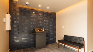 A reception area with a dark tiled wall, a reception desk, and a bench. - Grand Base Nagasaki City (Nagasaki)