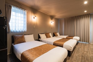 Ett hotellrum med tre sängar, ett trägolv och ett stort fönster med gardiner.