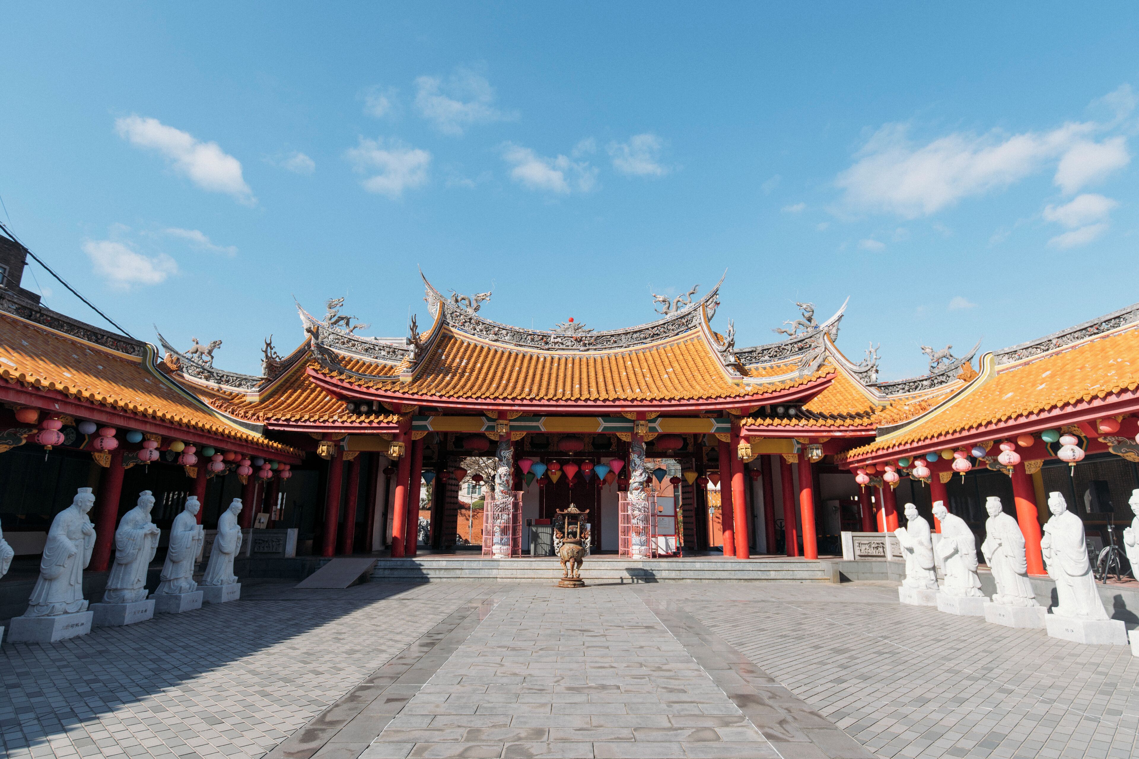 A traditional Chinese temple with ornate architecture, a central statue, and a paved courtyard.