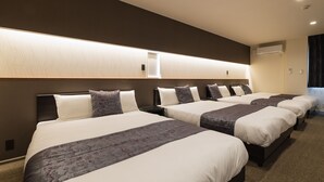 A hotel room with four beds aligned against a wall, each with a headboard and pillows. - Grand Base Nagasaki City (Nagasaki)