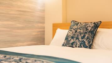 A neatly made bed with a patterned pillow and a blue and white blanket.