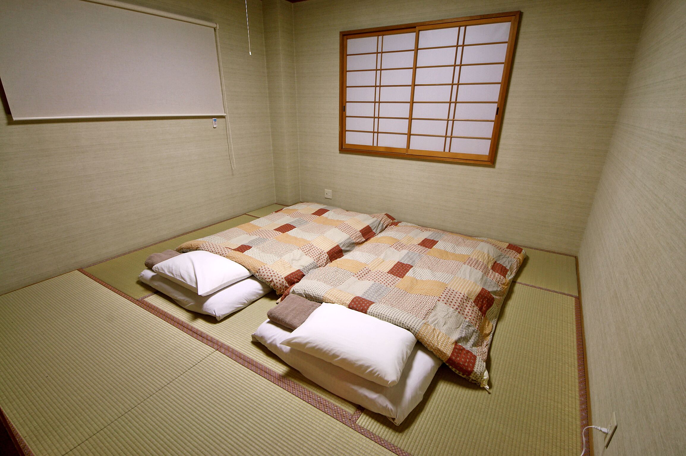 A traditional Japanese room with tatami flooring, a futon bed, and a shoji screen.