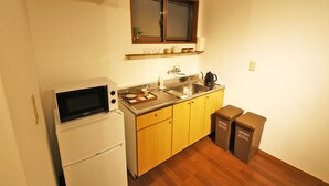 A compact kitchen with a microwave, sink, and wooden cabinets. - Sumica Apartments (Nikko)