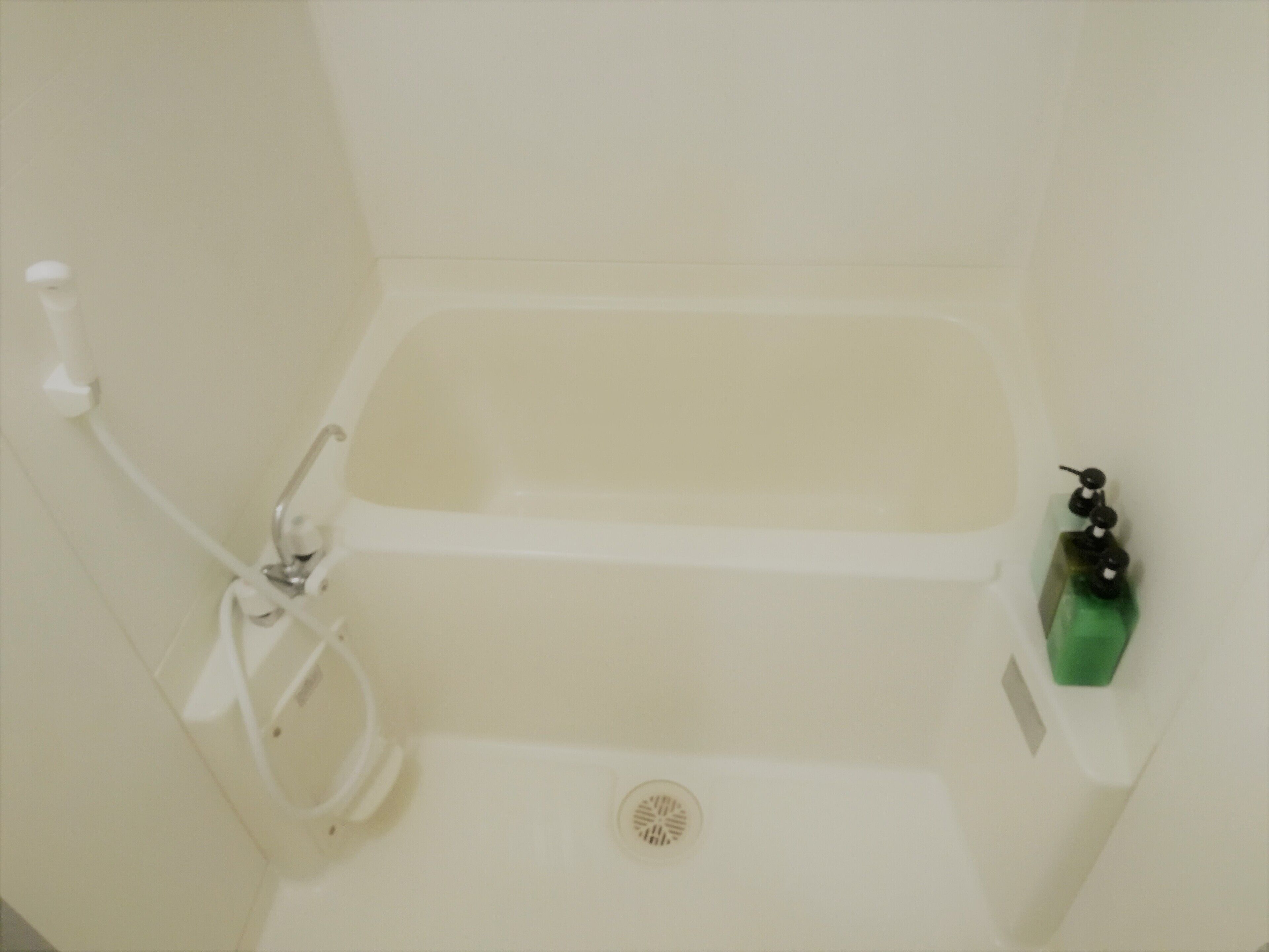 Eine Badewanne mit Duschbrause und Seifenspender.