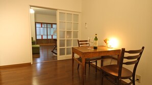 A dining area with a wooden table and chairs, a bottle of wine, and a lit candle. - Sumica Apartments (Nikko)