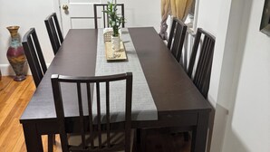 Un comedor con una mesa rectangular, seis sillas, un florero y un cuadro en la pared.