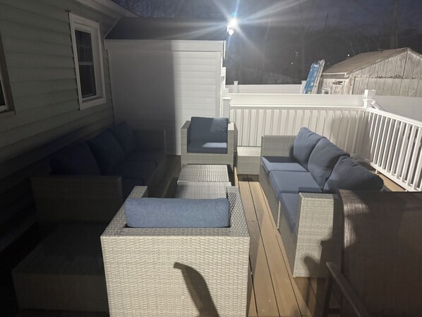 An outdoor deck with wicker furniture, including sofas and a table.