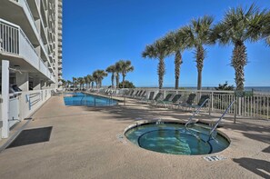 A pool area with a hot tub, lounge chairs, and palm trees. - Oceanfront Corner Condo in North Myrtle Beach! (North Myrtle Beach)