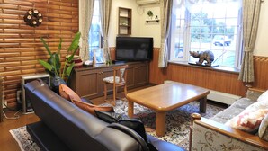 A living room with a sofa, a coffee table, a TV, and a decorative wreath on the wall. - Asahikawa Big Lodge 7 People (Asahikawa)