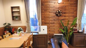 A cozy room with a wooden dining table, chairs, a sofa, and a wall-mounted heater. - Asahikawa Big Lodge 7 People (Asahikawa)