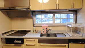 A compact kitchen with a dishwasher, a stove, a sink, and a window with a view of the outside. - Asahikawa Big Lodge 7 People (Asahikawa)