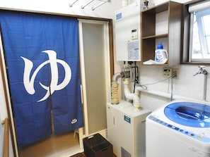 A bathroom with a blue towel, a white toilet, a sink with a soap dispenser, and a blue and white water heater.
