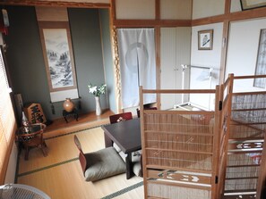 A traditional Japanese room with tatami flooring, a low table, a cushioned bench, and a sliding door.