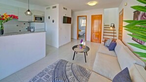 A modern living room with a sofa, a coffee table, and a kitchen area with a microwave. - Imperial Park by Interhome (Calpe/Calp)