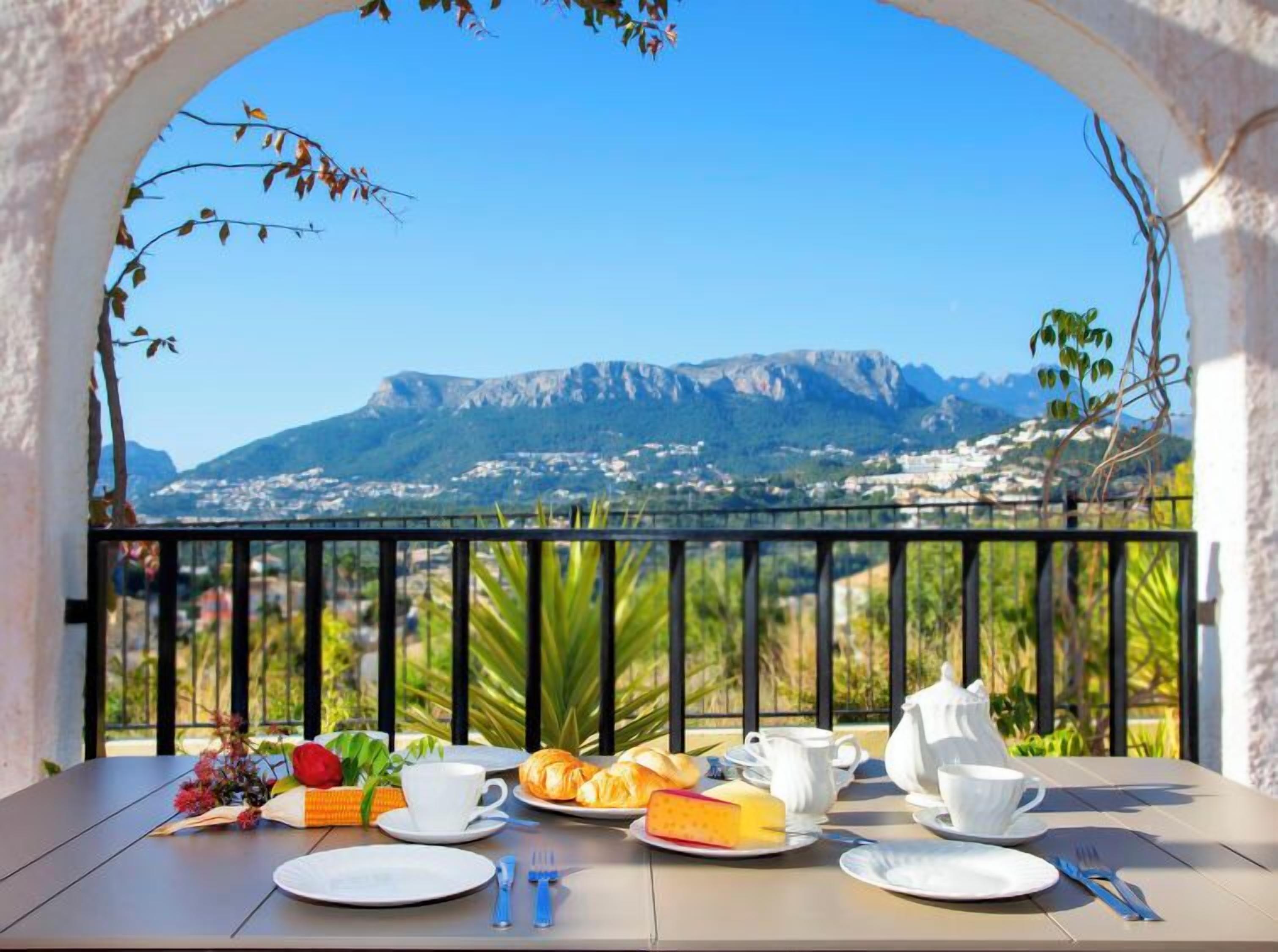 Ein Frühstückstisch mit Blick auf Berge, inklusive Berglandschaft und einem Dorf im Hintergrund.