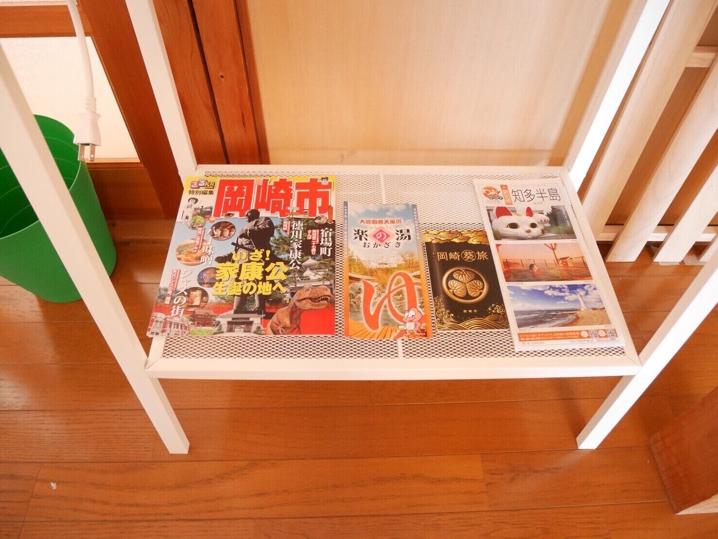 A magazine rack with various magazines on a white metal shelf.
