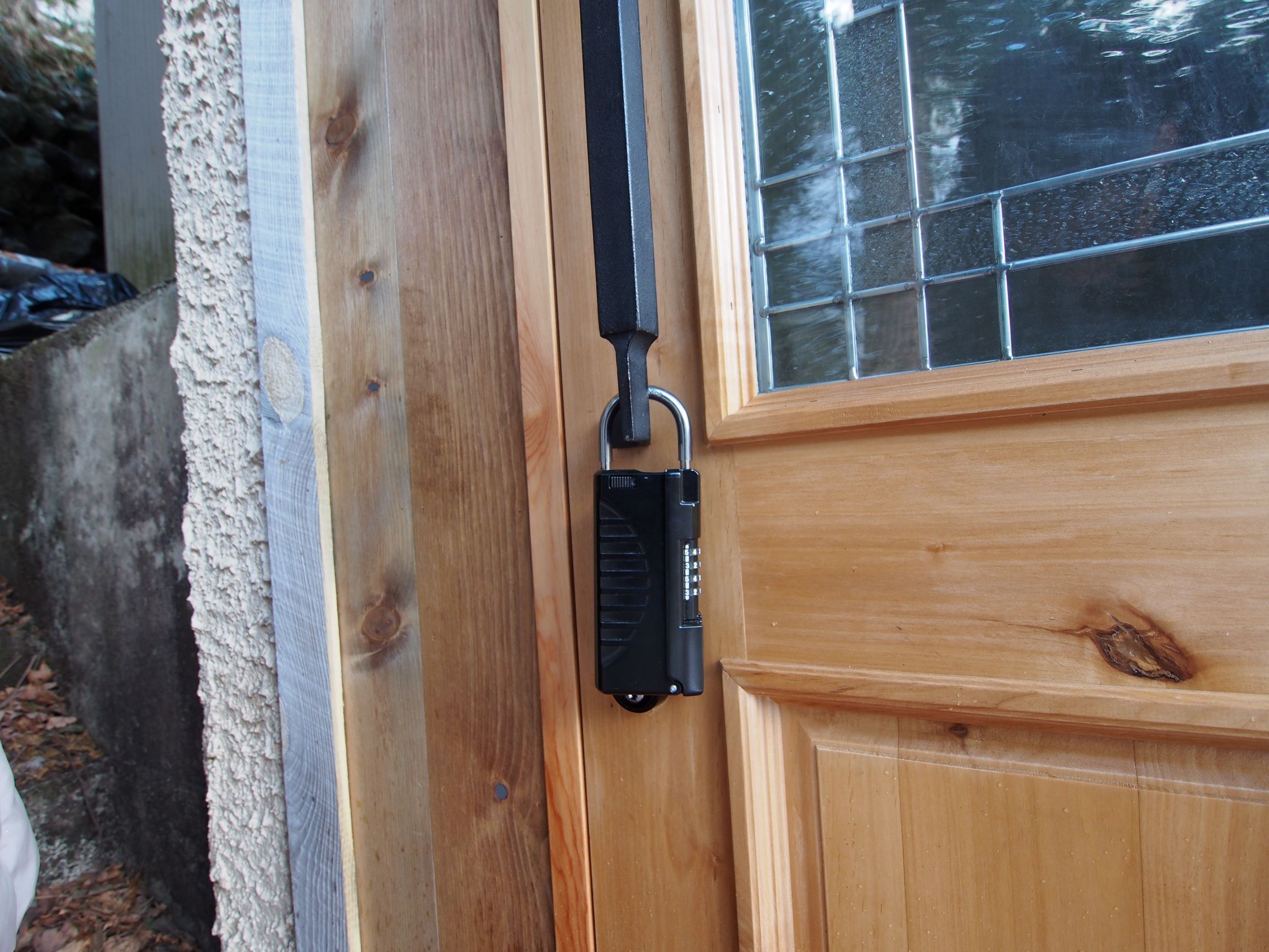 Una puerta de madera con un cerrojo electrónico negro y una ventana con diseño de cuadrícula.