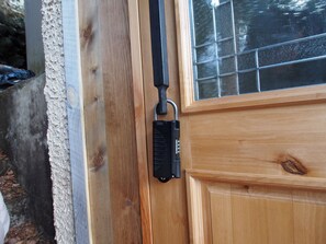 Una puerta de madera con un cerrojo electrónico negro y una ventana con diseño de cuadrícula.