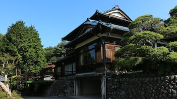 A traditional Japanese-style building with a stone wall and a wooden deck.