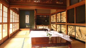 A traditional Japanese room with tatami flooring, sliding doors, and a wooden ceiling with intricate carvings. - Kougetsu Sanso (Hachioji)