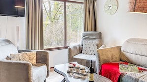Ein Wohnzimmer mit einer Couch, Sesseln, einem Couchtisch und einem Fernseher.