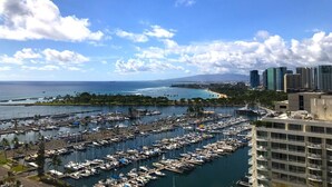Un puerto deportivo con numerosas embarcaciones amarradas, un cielo azul despejado y un paisaje urbano al fondo.