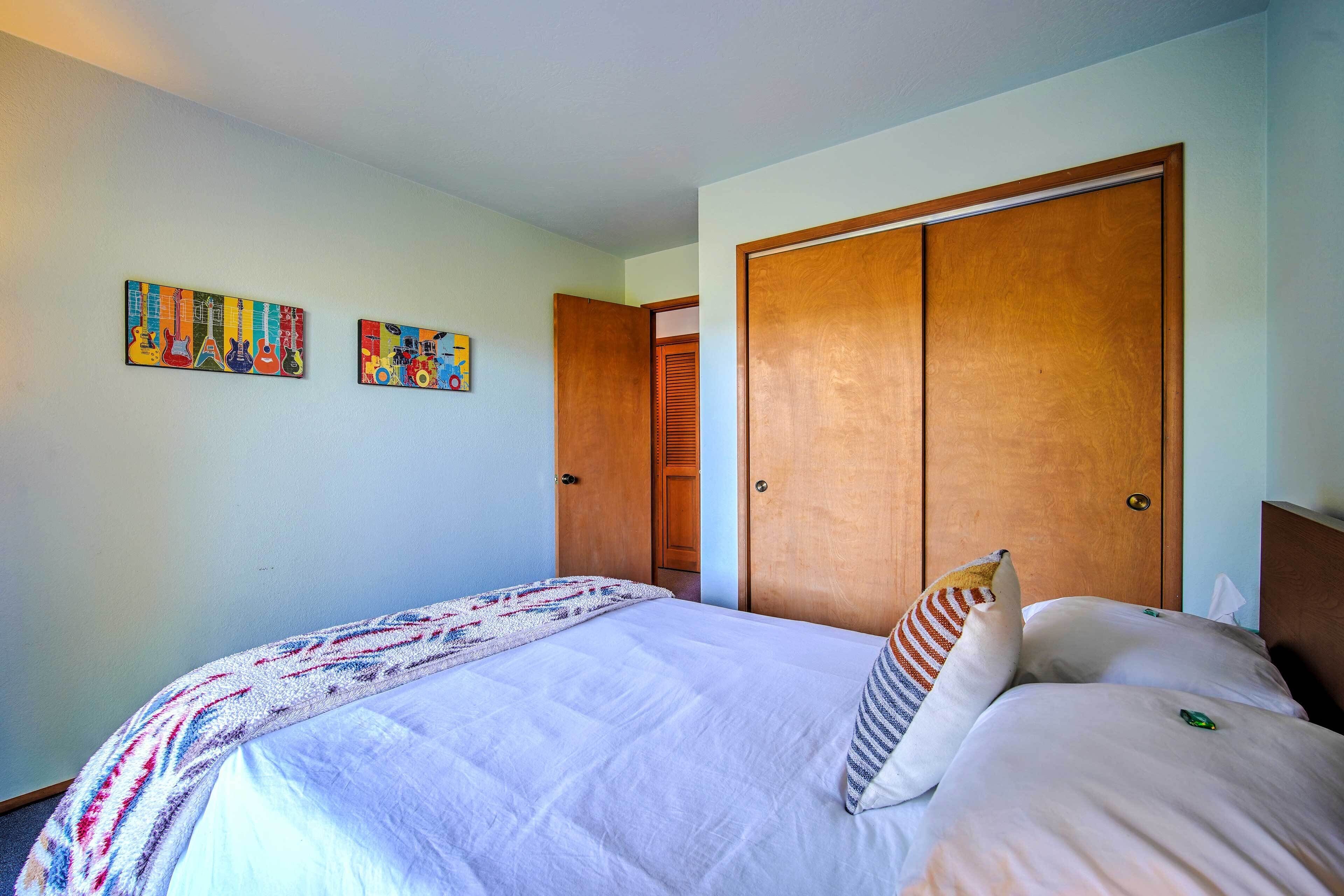 Un dormitorio con cama, un amplio armario de madera y dos cuadros decorativos.