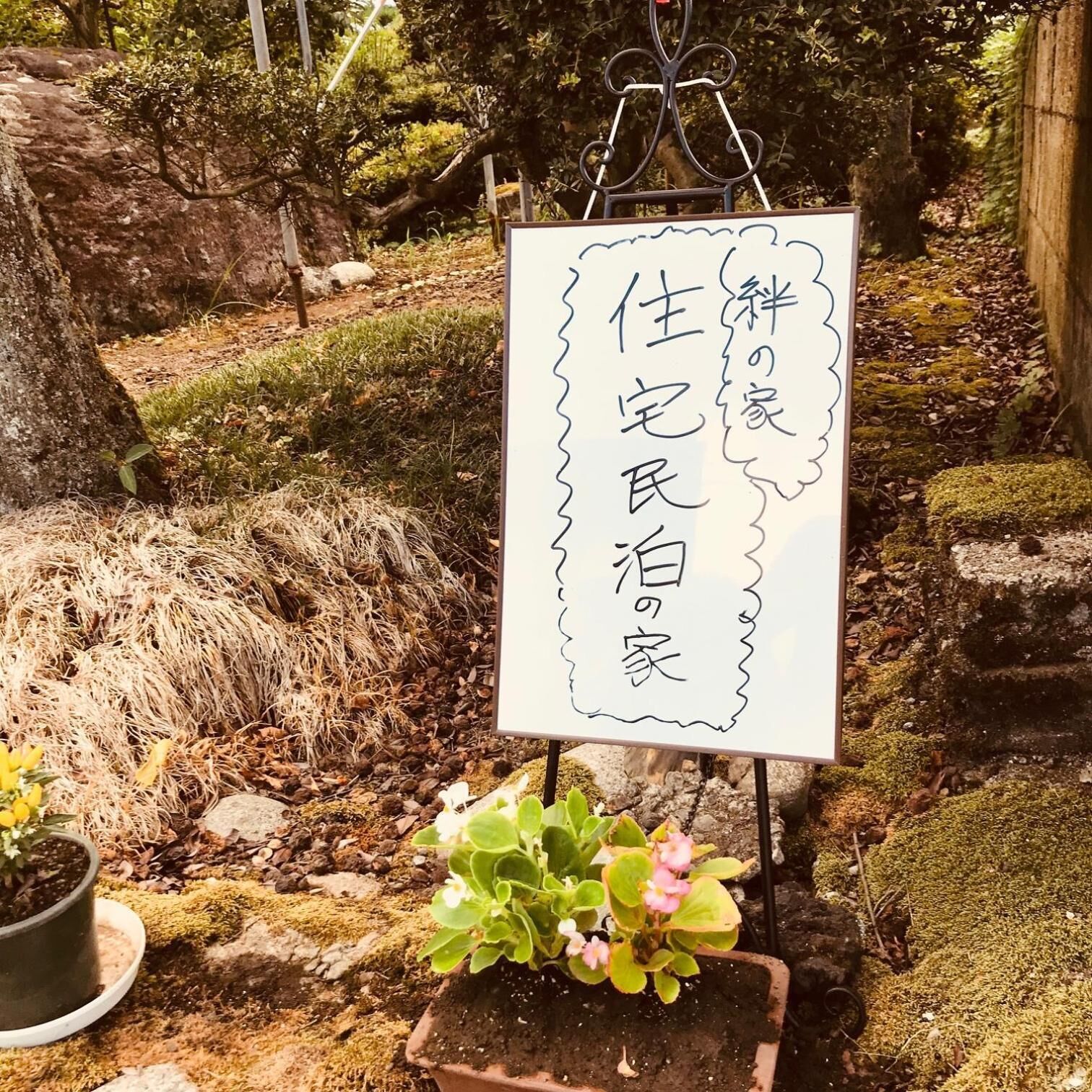 Ein Schild mit japanischen Schriftzeichen in einem Garten.