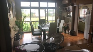 Ein Essbereich mit Tisch und Stühlen, im Hintergrund eine Küche und Blick ins Freie.