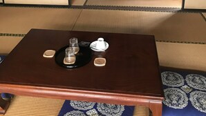 Ein traditioneller japanischer Raum mit Tatami-Boden, einem niedrigen Holztisch mit Teeservice und Futonbetten.