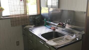 A compact kitchen with a sink, a mirror, and a window with a view of greenery outside.