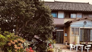 Ein traditionelles japanisches Haus mit Garten, mit Topfpflanzen und einer kleinen Sitzgelegenheit im Freien.