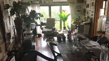 A home office with a desk, chairs, potted plants, and various office supplies.